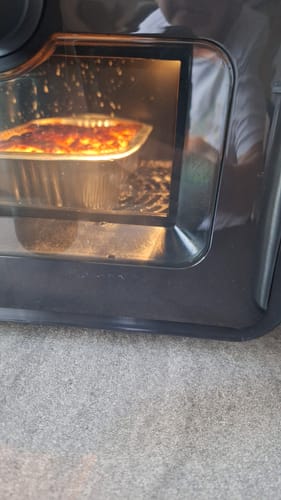 Customer's Air Fryer Novio StonePro with a metal container of food cooking inside the lit oven interior.