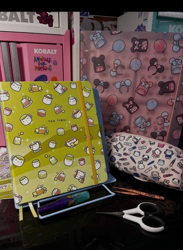 Customer's Tea Time A5 Wide Yearly Planner resting on a stand with a pen, surrounded by cute stationery.