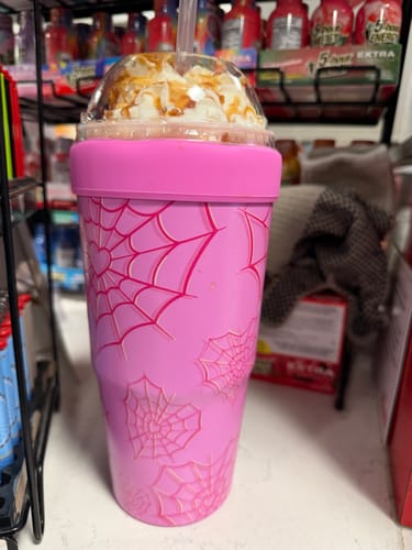 Customer's Pink Widow To-Go Buddy cup with heart-shaped web patterns, filled with a whipped coffee drink.