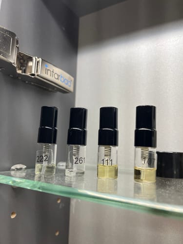 Customer's Tester Set with four small fragrance sample bottles numbered 222, 261, 111, and 107 on a shelf.