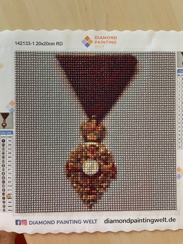Customer's Diamond Painting eigenes Bild showing a completed design of a dark red medal with a centered white jewel.