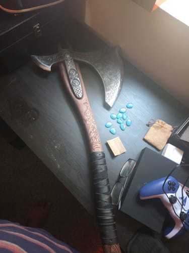 Customer's heavy decorative axe from Strengthen Your Blade resting on a dark desk next to gaming accessories.