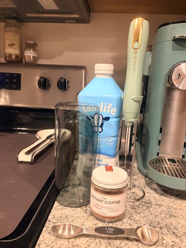 Customer's FLUR Instant Coffee jar with measuring spoon and milk bottle on a kitchen counter.