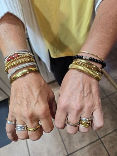 Customer's hands wearing multiple gold-toned and beaded bracelets and rings from the Waterproof Jewelry Bundle