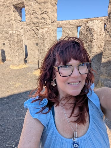 Customer's selfie at a stone monument, reviewer wearing glasses and blue top.