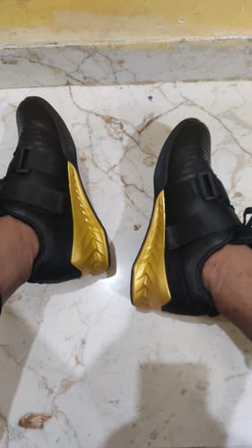 Customer's Squat Pro S1 sneakers in black with gold accents worn on their feet