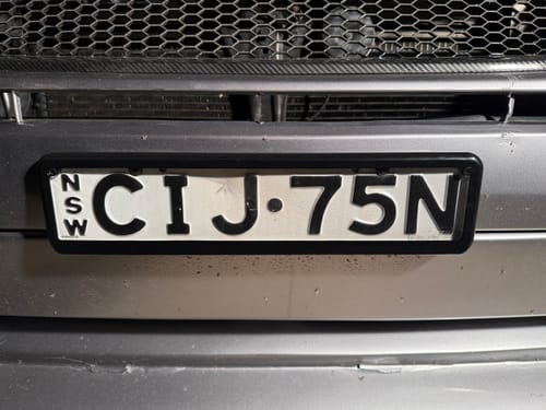 Reviewer's Kingpin Slimline front number plate cover installed on a car bumper.