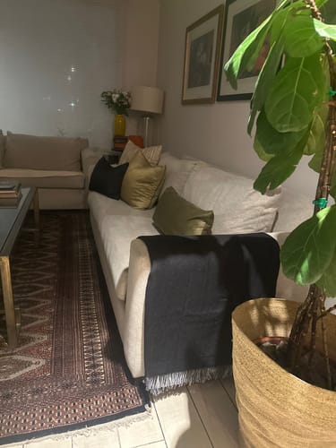 Customer's Manta Algodón Y Lino Puntos, una manta oscura colocada sobre un sofá claro en una sala de estar.