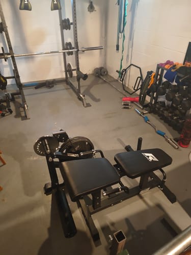 Reviewer's black exercise bench in a home gym, showing adjustable parts and setup.