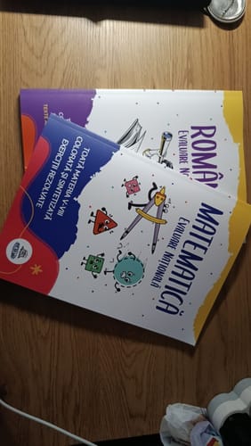 Reviewer's Bacademia National Evaluation study guides for Romanian and Mathematics placed on a wooden surface.