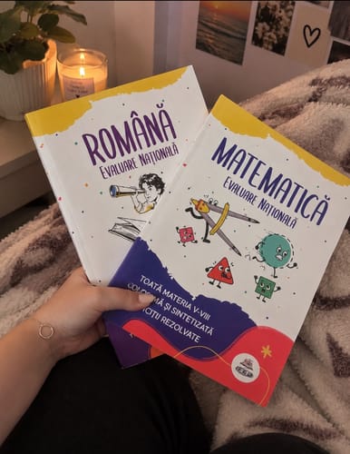 Reviewer's hand holding two Bacademia Pachet Evaluare Națională textbooks for Romanian and Mathematics.