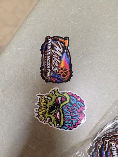 Customer's custom stickers featuring colorful logo designs for a powder coating company and a skull graphic.