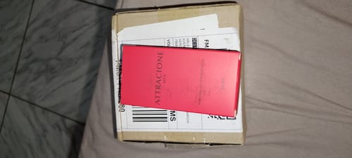 Customer's Attracione Men perfume box in vibrant red, resting on a cardboard shipping package.