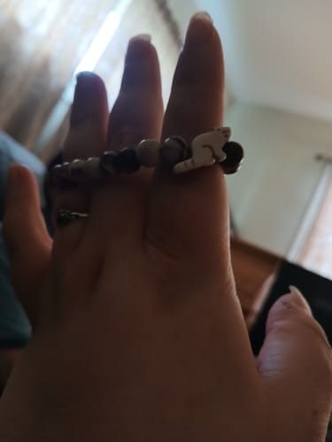 Customer's hand wearing the Dash Bracelet, featuring brown beads and a small white red panda charm.