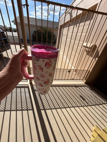Customer's floral patterned tumbler with a bright pink ONE Lid held outdoors.