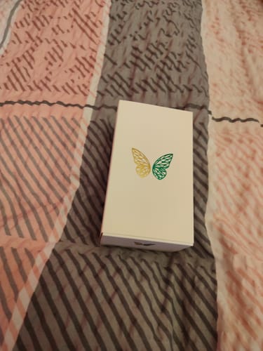 Customer's white Kiage 133 perfume box featuring a decorative butterfly illustration on a striped bedspread.