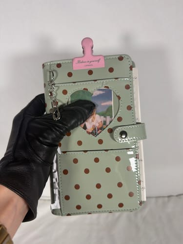Customer's mint green Mint Dot journal featuring a glossy polka dot cover, held by a hand in a black glove.
