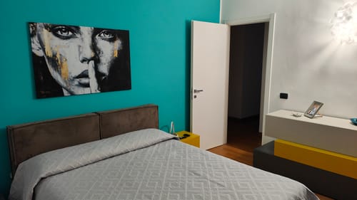 Customer's Il Silenzio d'Oro canvas print hanging on a bright teal bedroom wall above a gray bed.