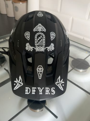 Customer's black helmet decorated with various white Lucky Dip vinyl stickers.