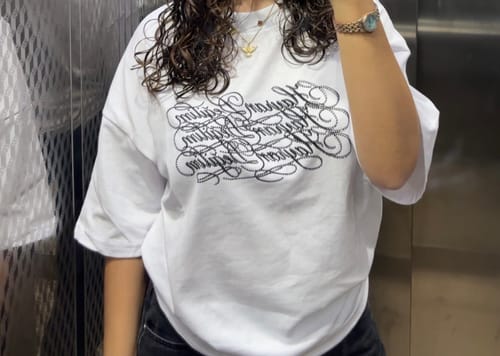 Customer's white Hayran Değilim baskılı boxy tişört giymiş, asansörde ayna karşısında duran bir kişi.