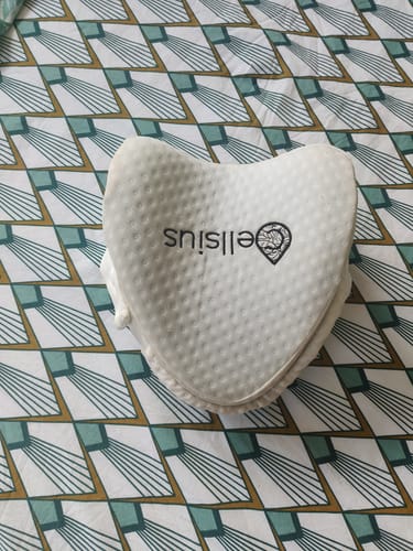 Customer's white Cellsius orthopedic knee pillow resting on a patterned bed sheet.
