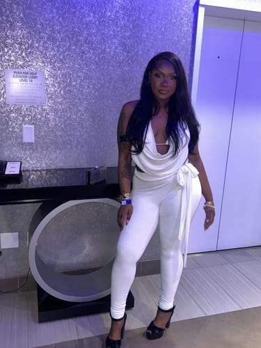 Reviewer wearing a white matching outfit set with a draped top and fitted pants, paired with black heels.