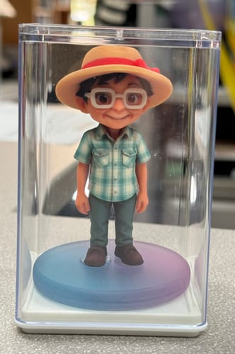 Customer's Custom 3D Action Figure, a chibi-style figurine wearing a sun hat and plaid shirt in a clear display case.