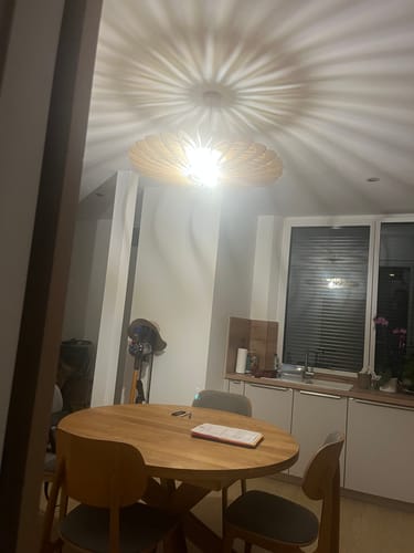 Reviewer's NEO teinté Chêne suspension allumée, projetant des ombres rayonnantes au plafond de la cuisine.