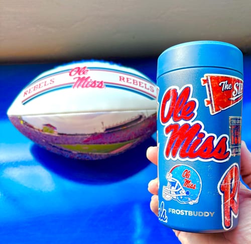 Reviewer's blue Ole Miss Rebels Universal Buddy can cooler held in a hand next to a football