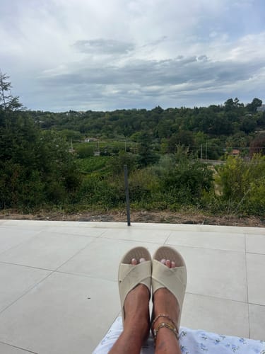Customer's HappySandals Stockholm worn outdoors on a sunny terrace overlooking a scenic landscape.