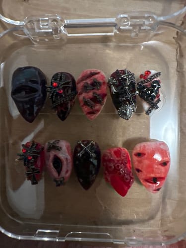 Reviewer's set of Crimson Ritual nails featuring gothic charms, textured skulls, and spiderwebs in a clear tray.