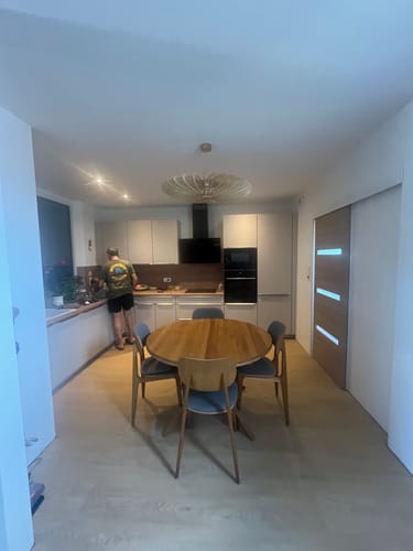 Customer's NEO teinté Chêne suspension installée dans une cuisine avec une personne en arrière-plan.