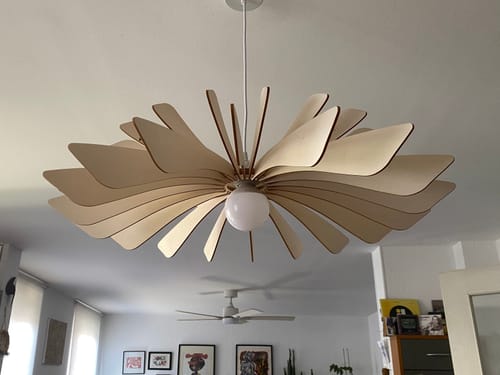 Customer's Aurora suspension light installed in a bright room, showcasing its light-colored wooden petals.