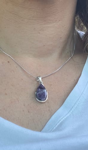 Customer's teardrop-shaped violet kämmérérite pendant on a silver chain worn around the neck.