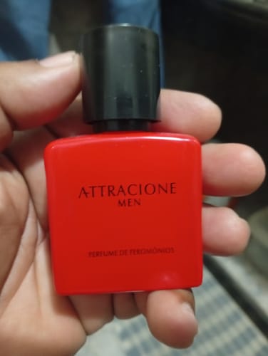 Customer's Attracione Men perfume bottle held in hand, showing the bright red square container and black cap.
