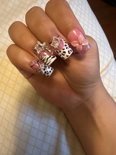Customer's Pink Sacrament press-on nails on hand, showing pink leopard print, 3D floral accents, and silver charms.