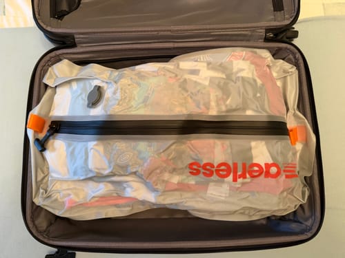 Customer's Aerless Luggage Tag inside a partially packed suitcase with a clear compression storage bag.
