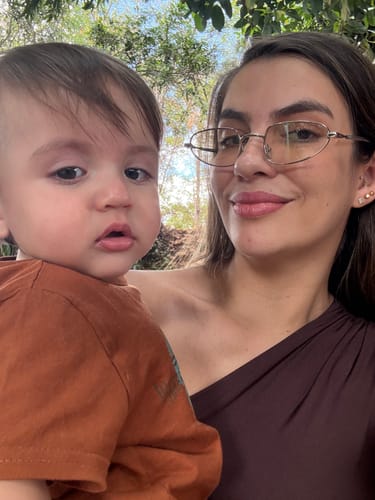 Reviewer wearing elegant Óculos de Sol Amalfi while holding a child.