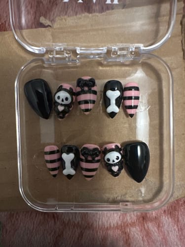 Customer's Bone Candy nail tips with pink-and-black striped, skull, and bone designs arranged in a plastic case.