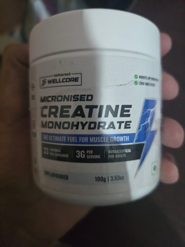 Customer's hand holding a white tub of Wellcore Micronised Creatine Monohydrate