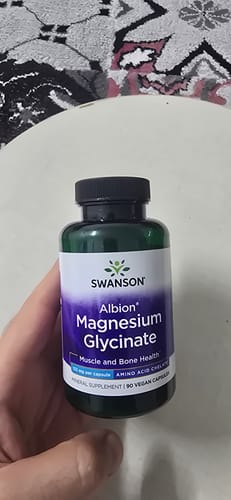 يد المراجع تحمل عبوة مكمل Swanson Albion Magnesium Glycinate الأخضر والأرجواني