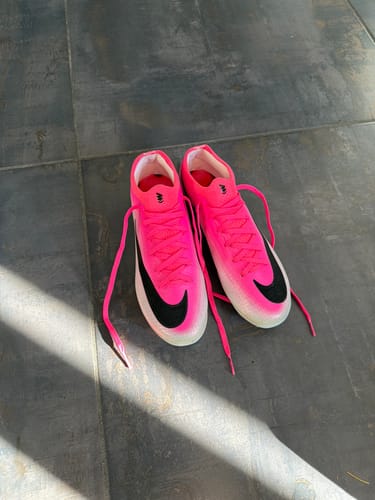 Customer's pair of Nike Mercurial Vapor 17 Elite soccer cleats in vibrant pink, viewed from above on a dark floor.