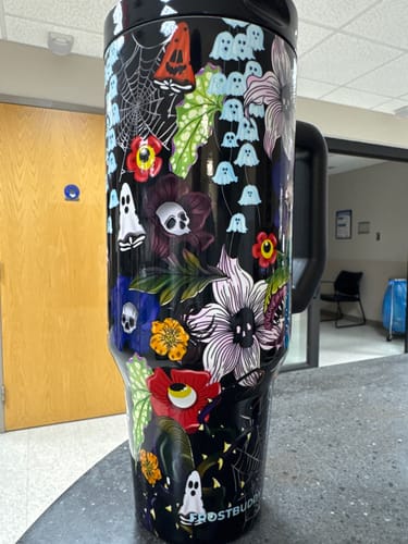Customer's Thicc Buddy 40oz Toxic Bloom tumbler, black with ghost and colorful floral patterns, sitting on a counter.
