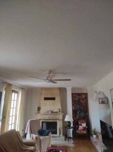 Reviewer's Mistral teinté Chêne ventilateur de plafond installé dans un salon au-dessus d'une cheminée.