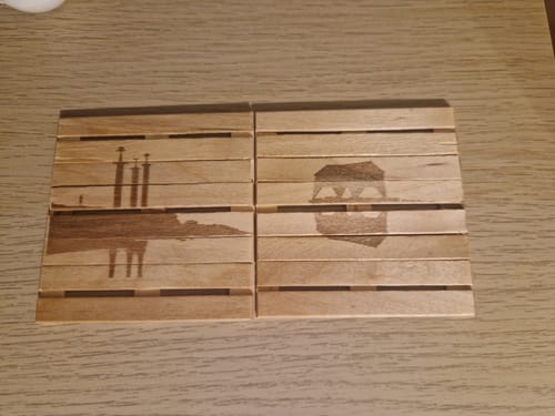Customer's AtomStack Swift laser engravings on four light wooden slats, featuring dark geometric designs.