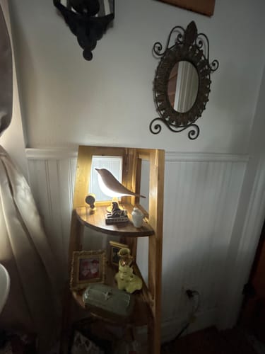 Customer's Glow Bird lamp glowing warmly on a wooden shelf in a room with a decorative mirror.