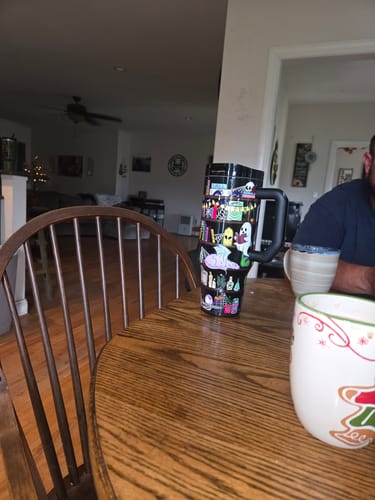 Customer's Thicc Buddy 40oz mug with a dark Halloween-themed design sitting on a wooden table.