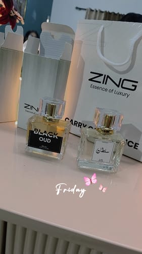 Customer's Black Oud and another perfume bottle from Zing next to branded shopping bags on a surface.