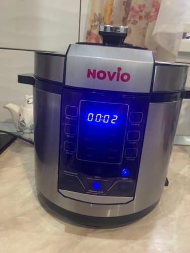Customer's Novio SteelCook multicooker on a kitchen counter with a glowing blue digital display showing two minutes.