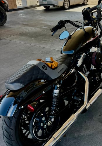 Customer's Born Scum X Saddlemen Step Up Seat installed on a black motorcycle at a gas station.